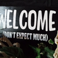 Welcome Don't Expect Much Entryway Sign